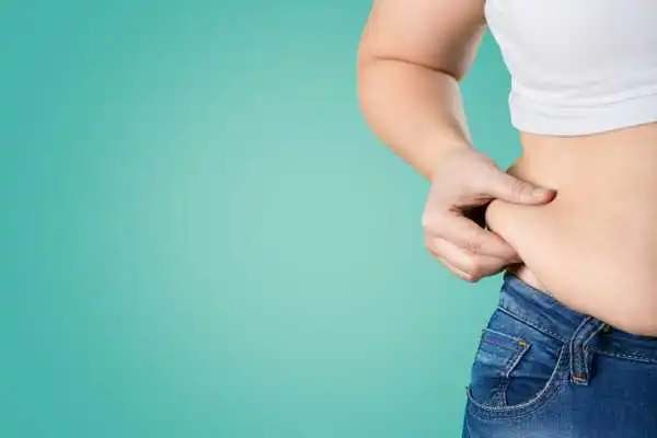 Image of woman pinching her love handles to show weight gain Hampshire